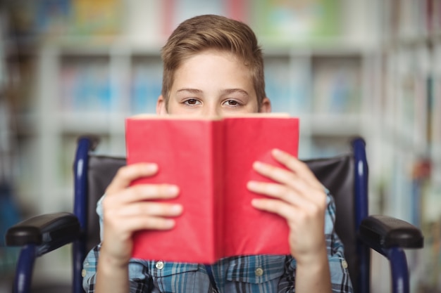 Portret niepełnosprawny uczeń trzyma książkę w bibliotece