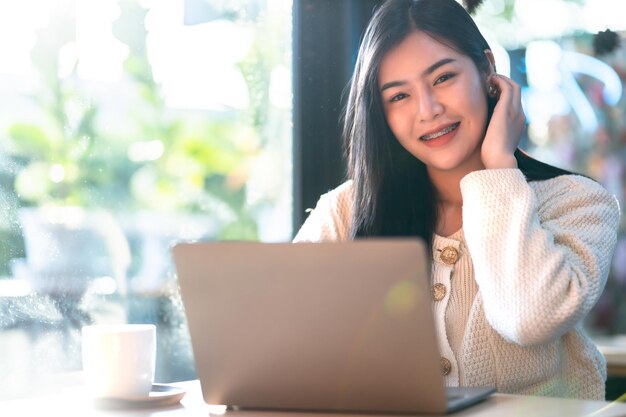Portret niezależny biznes piękny pozytywny uśmiech młoda azjatycka kobieta online pracująca z laptopem w domu w salonie w pomieszczeniu lub kawiarni Styl życia biznesu