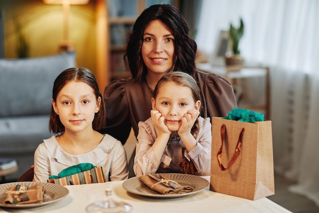 Portret nowoczesnej żydowskiej matki z dwójką dzieci patrząc na kamerę siedząc przy stole i