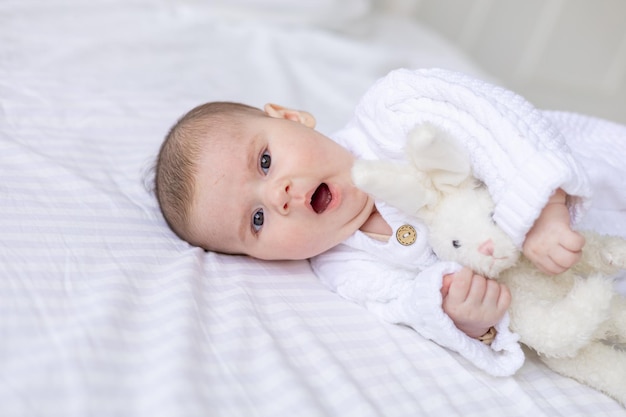Portret noworodka ziewającego dziecka w łóżeczku w białym ciepłym kombinezonie na białym izolowanym bawełnianym łóżku dziecko śpi w zbliżeniu