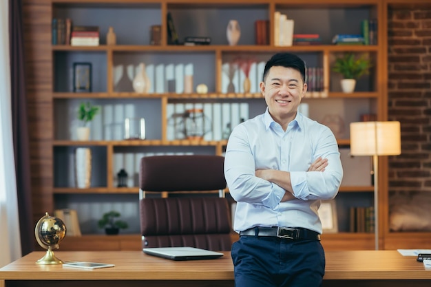 Portret odnoszącego sukcesy biznesmena pracującego w klasycznym biurze Azjatycki uśmiechnięty i szczęśliwy patrzący na kamerę ze skrzyżowanymi rękami
