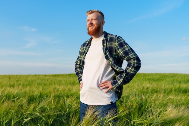 Portret odnoszącego sukcesy rolnika Mężczyzna stoi na polu pszenicy w koszuli i dżinsach Agronom cieszy się z przyszłych zbiorów