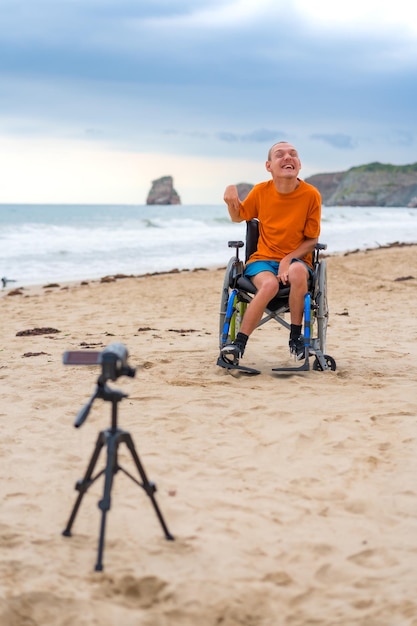 Zdjęcie portret osoby niepełnosprawnej na wózku inwalidzkim na plaży nagrywającej film