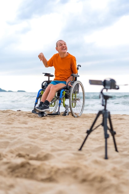 Portret osoby niepełnosprawnej na wózku inwalidzkim nagrywającej film na plaży