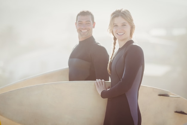 Portret para z surfboard pozycją na plaży