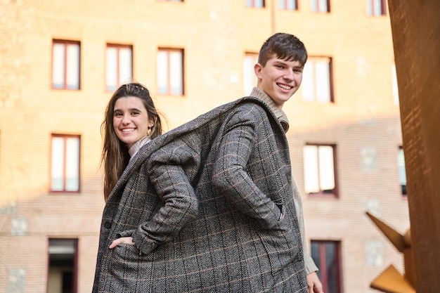 Portret pary dzielącej płaszcz młoda para uśmiechająca się