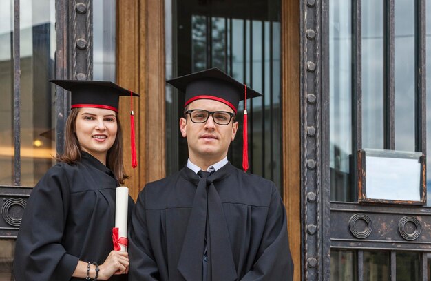 Zdjęcie portret pary w sukniach absolwentów stojących przy drzwiach