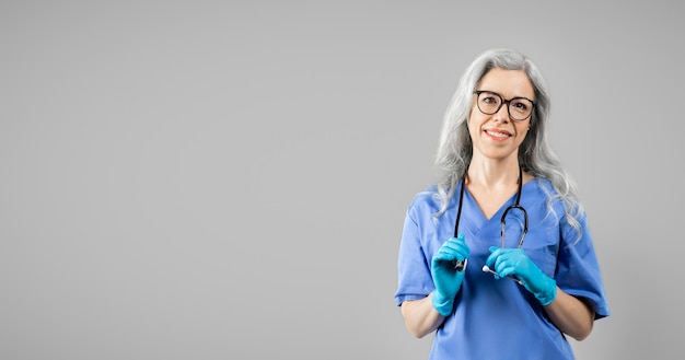 Portret pewna pracownik medyczny dama pozuje na szarym tle