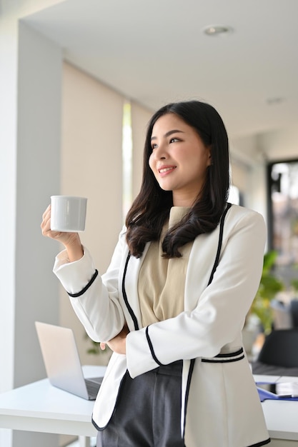 Portret pewnej azjatyckiej bizneswoman marzącej na jawie popijając kawę