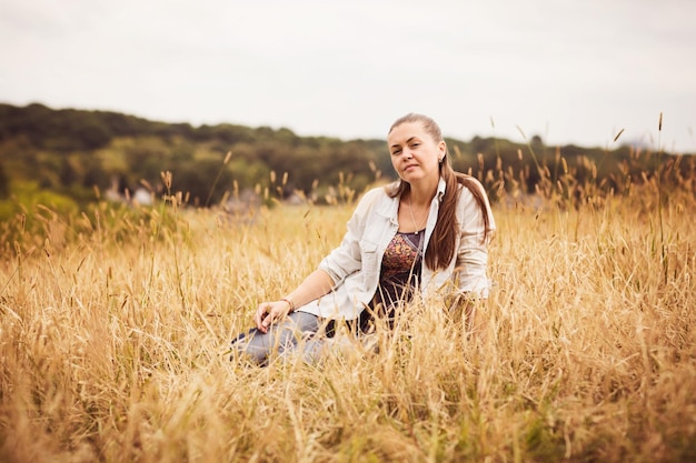 Portret pewnej siebie, autentycznej kobiety siedzącej na polu na wsi