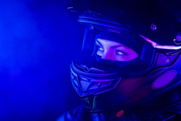 Zdjęcie portret pewnej siebie motocyklistki w zamkniętym hełmie motocyklowym młody kierowca motocyklista niebieski neon