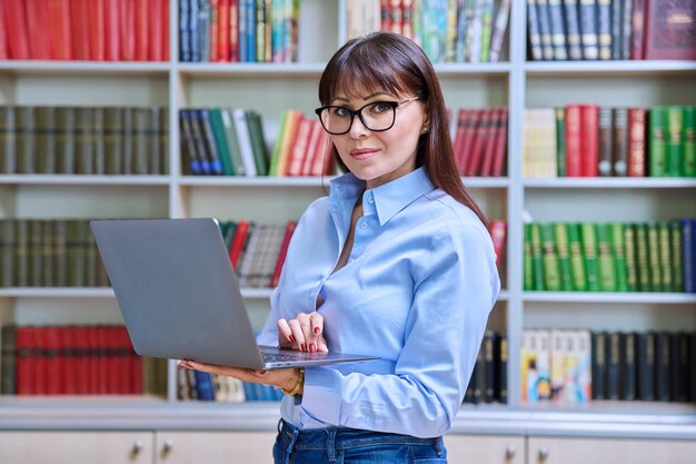 Zdjęcie portret pewnej siebie nauczycielki z laptopem w bibliotece