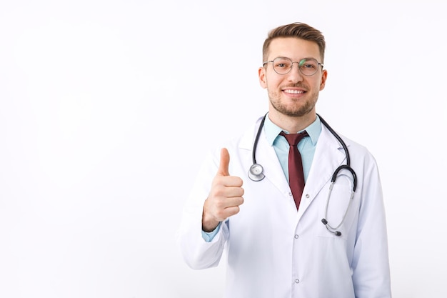 Portret pewny siebie młody lekarz medycyny na białym tle lekarz pokazuje symbol ok