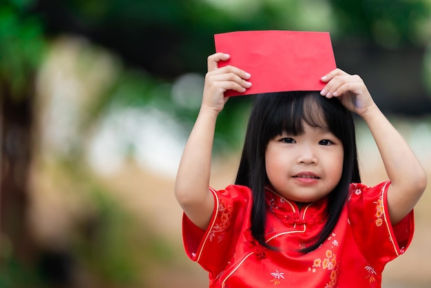 Portret piękna azjatycka dziewczynka w sukience CheongsamTajlandia ludzieSzczęśliwego chińskiego nowego roku koncepcjaSzczęśliwa mała azjatycka dziewczynka w chińskim tradycyjnym stroju