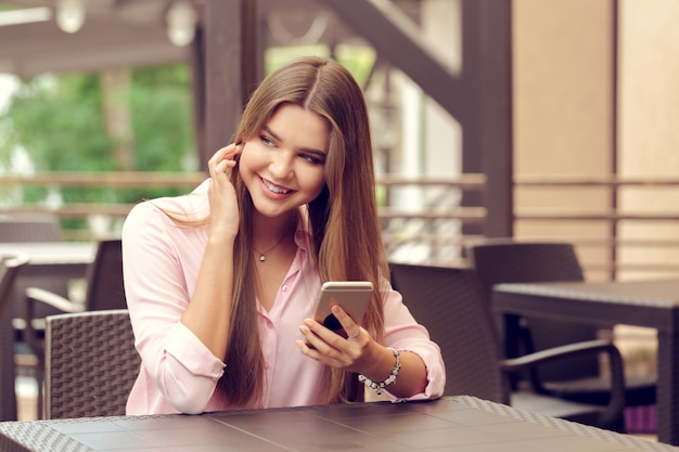 Portret piękna dziewczyna używa jej telefon komórkowego w kawiarni