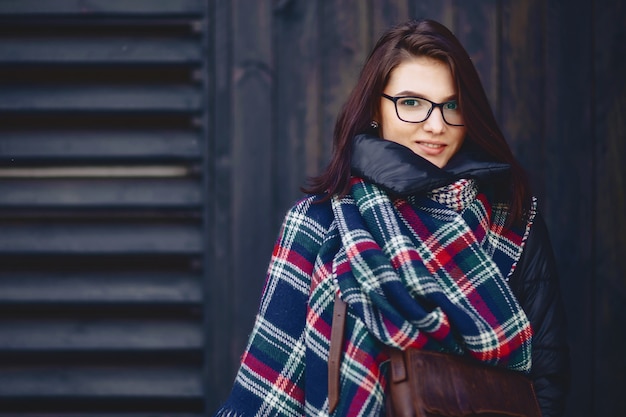 Portret piękna dziewczyna w eyeglasses i szaliku przeciw drewnianej ścianie