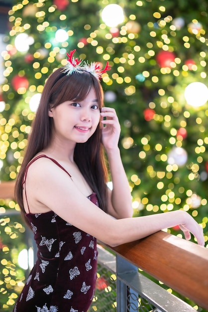 Portret piękna młoda azjatycka kobieta czerwona sukienka kostium i pozdrowienia bożonarodzeniowe zdjęcie dekoracja paczki na choince lekkie okrągłe tło bokeh Dekoracja podczas świąt Bożego Narodzenia i Nowego Roku