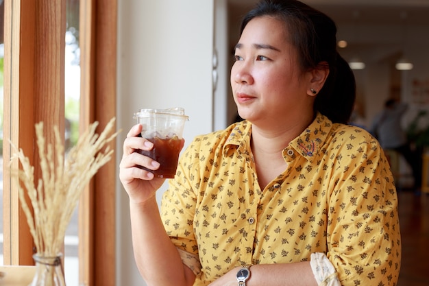 Portret piękna młoda Azjatycka kobieta trzyma filiżankę lodu w kawiarni
