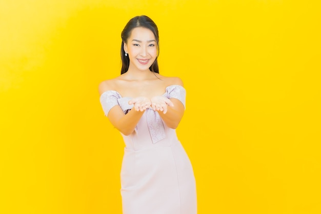 Portret piękna młoda azjatycka kobieta uśmiecha się i pozuje na kolorowej ścianie