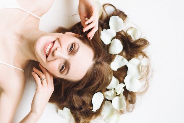 Zdjęcie portret piękna młoda kobieta z biel róży płatkiem na białym tle. relaks i spa