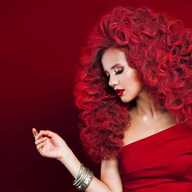 Portret piękna młoda kobieta z czerwonym włosy na czerwieni ścianie