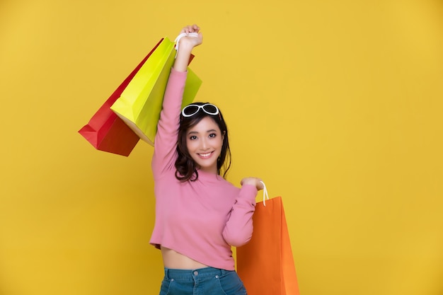 Portret piękna szczęśliwa młoda kobieta uśmiecha się rozochoconego i trzyma torba na zakupy
