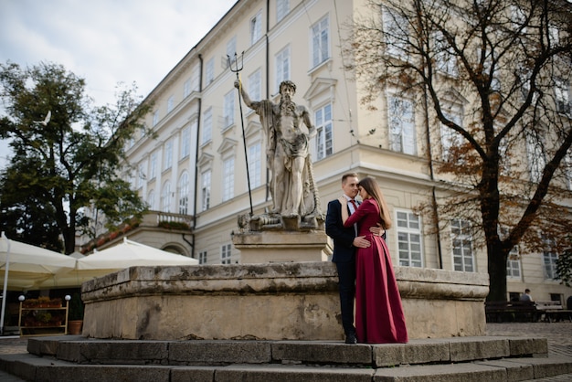 Portret piękna uśmiechnięta miłości para siedzi blisko fontanny outdoors w mieście.