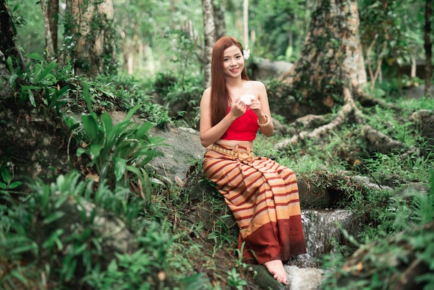 Portret piękne azjatykcie kobiety przy siklawą w dżungli