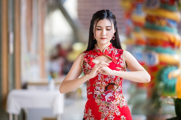 Portret piękne uśmiechy Azjatycka młoda kobieta ubrana w czerwony tradycyjny chiński cheongsam, na Chiński Nowy Rok Festiwal w chińskiej świątyni