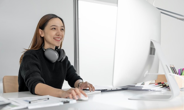 Portret pięknego azjatyckiego freelancera przy użyciu komputera stacjonarnego w domowym biurze