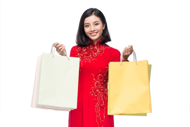 Portret pięknej azjatyckiej kobiety na tradycyjnym stroju festiwalu Ao Dai trzymając torby na zakupy.