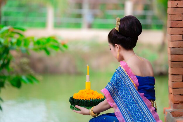 Portret pięknej azjatyckiej kobiety w tajskim stroju tradycyjnej modlitwy trzymaj kratong, aby dołączyć do festiwalu loy kratong w tajlandii