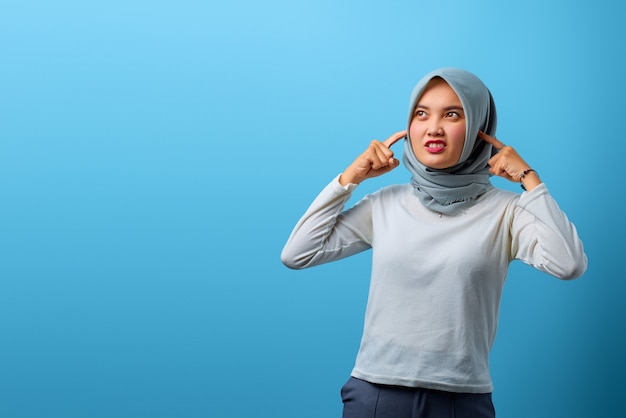 Portret pięknej azjatyckiej kobiety wściekłej i zakrywającej uszy palcem