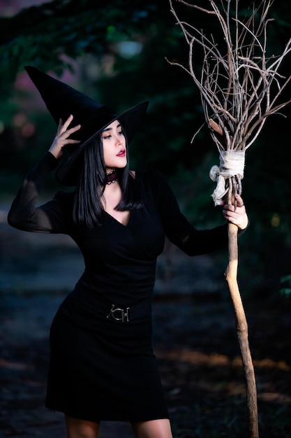 Zdjęcie portret pięknej azjatyckiej seksownej kobiety nosi czarny kostium czarownicy z koncepcją festiwalu miotłyhalloween