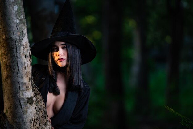 Portret pięknej azjatyckiej seksownej kobiety nosi czarny kostium czarownicy z koncepcją festiwalu miotłyHalloween