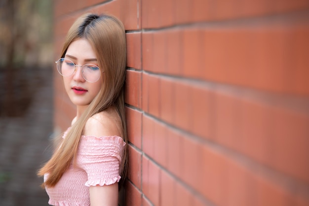 Portret pięknej azjatyckiej szykownej dziewczyny nosić czarną sukienkę pozować do zrobienia zdjęcia na ceglanej ścianieStyl życia nastolatków z TajlandiiNowoczesna kobieta szczęśliwa koncepcjaStyl koreański