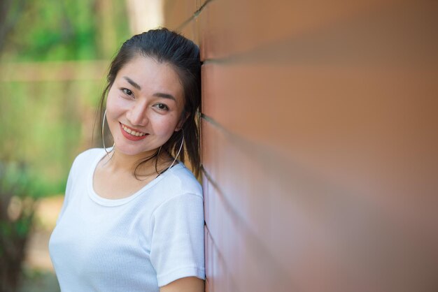 Portret pięknej azjatyckiej szykownej dziewczyny pozuje do zrobienia zdjęcia na ceglanej ścianieStyl życia nastolatków z TajlandiiNowoczesna kobieta szczęśliwa koncepcja