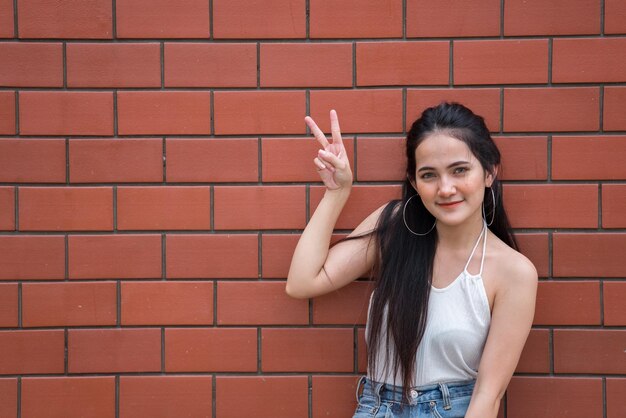 Portret pięknej azjatyckiej szykownej dziewczyny pozuje do zrobienia zdjęcia na tle ścianyStyl życia nastolatków z TajlandiiNowoczesna kobieta szczęśliwa koncepcja Styl punk rocka