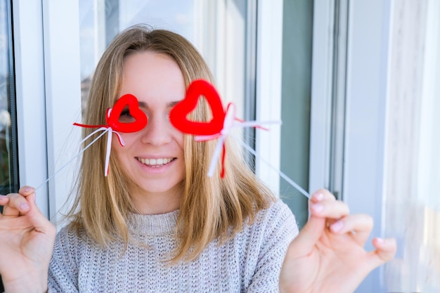 Portret pięknej blondynki szczęśliwa kobieta trzyma symbol serca. Dwa czerwone serca. Dziewczyna przy selfie. Sam na Walentynki. Miłość. Romantyczny. Biały sweter, emocje