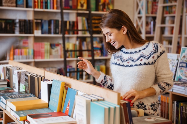 Portret pięknej brunetki szukającej książki w sklepie
