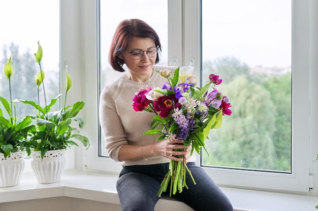 Portret pięknej dojrzałej kobiety z bukietem w domu