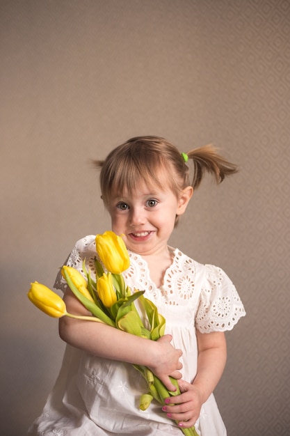 Portret pięknej dziewczynki z bukietem żółtych tulipanów