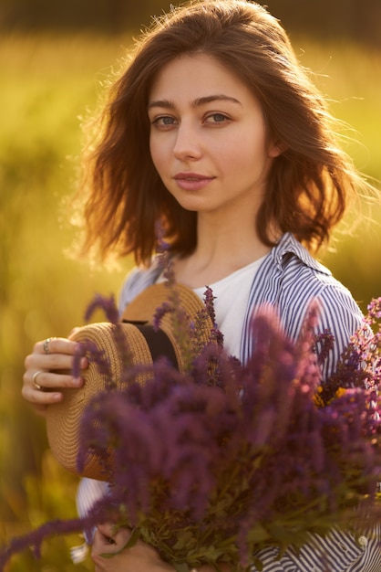 Portret pięknej dziewczyny z bukietem lawendy. Światło słońca i piękna zmysłowość. Dziewczyna cieszy się chwilą