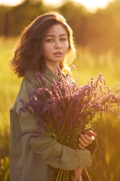 Portret pięknej dziewczyny z bukietem lawendy. Światło słońca i piękna zmysłowość. Dziewczyna cieszy się chwilą