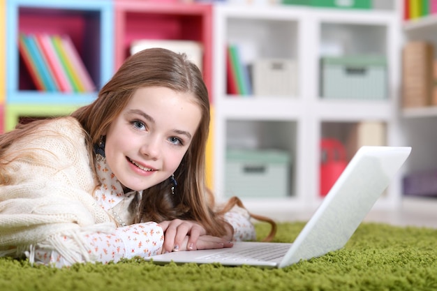 Portret pięknej emocjonalnej słodkiej dziewczyny korzystającej z laptopa