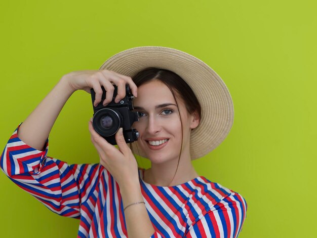 Portret pięknej fotografki fotografującej z bliska. Powiedz ser. Młoda uśmiechnięta kobieta trzyma aparat odizolowywający na zielonym tle