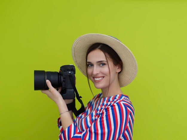 Portret pięknej fotografki z bliska. Powiedz ser. Młoda uśmiechnięta kobieta trzyma aparat i myśli, jak zrobić zdjęcie odizolowane na zielonym tle.