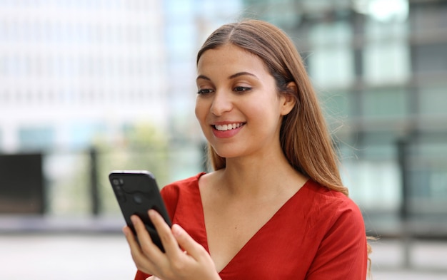 Portret Pięknej Kobiety Biznesu Dorywczo Wysyłającej Wiadomość Z Aplikacją Do Czatowania Telefonu Komórkowego Z Nowoczesnymi Drapaczami Chmur W Tle