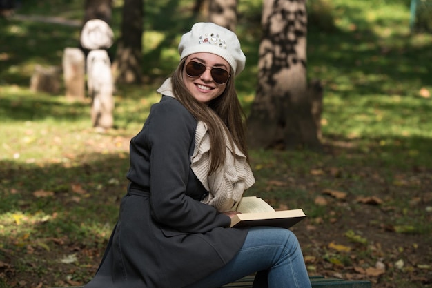 Portret pięknej kobiety brunetka czytającej książkę w jesiennym parku