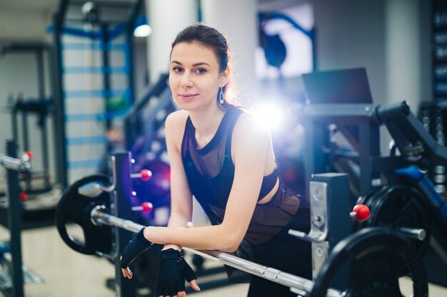 Portret pięknej kobiety fit odpoczynek po podniesieniu brzana w centrum fitness. Młoda sportowa muskularna kobieta robi sobie przerwę między powtórzeniami. Zbliżenie. Pojęcie zdrowego życia.